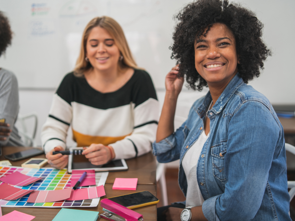 Two smiling student gathered around a table filled with handouts.
