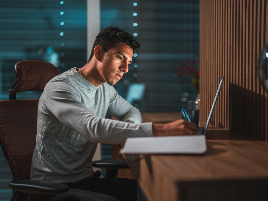A PhD student writing notes at a desk.