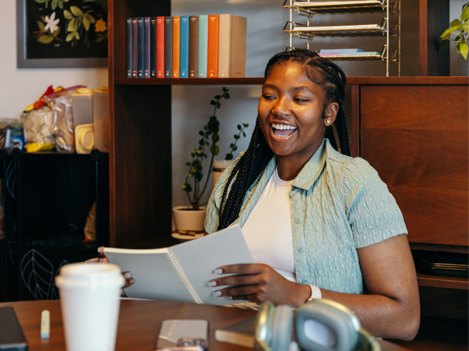 A PhD student smiles while holding a notebook.