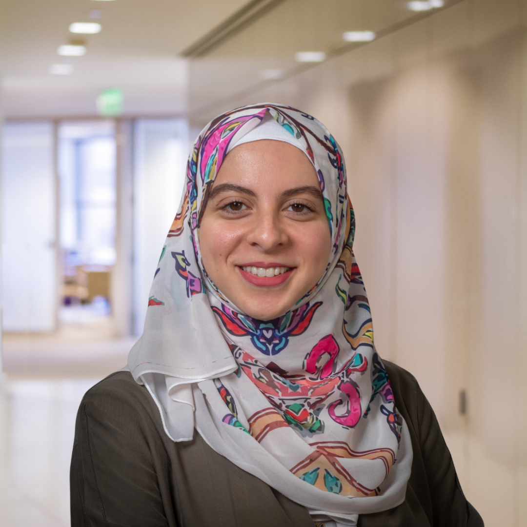 Headshot of Ala Mokhtar, a smiling woman in a patterned colorful hijab and a dark top.