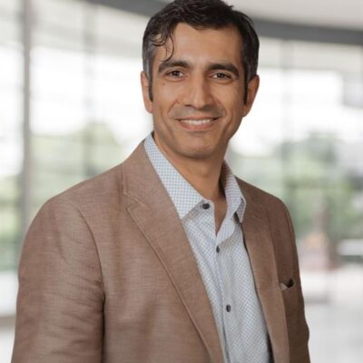 Headshot of Amir Akbari, a smiling man with dark hair, in a light brown blazer.