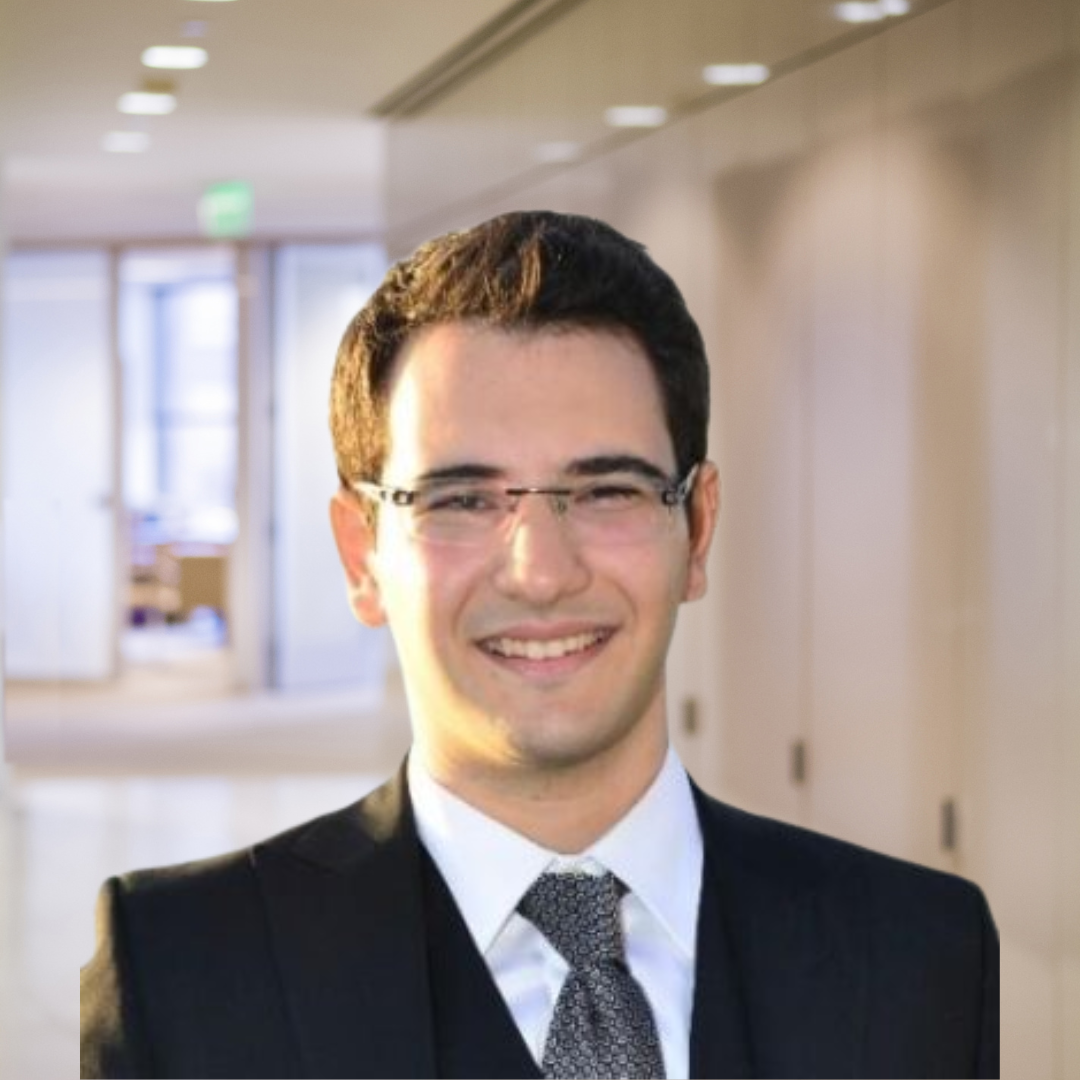 Headshot of Berk Gorgulu, a smiling man with dark hair, glasses, wearing a black suit.
