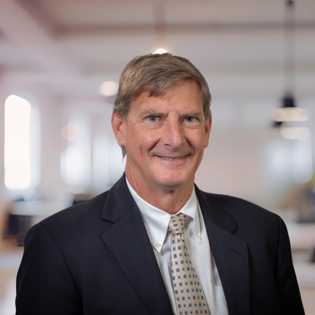 Headshot of Glen Randall, a smiling man with short brown hair, wearing a dark suit.