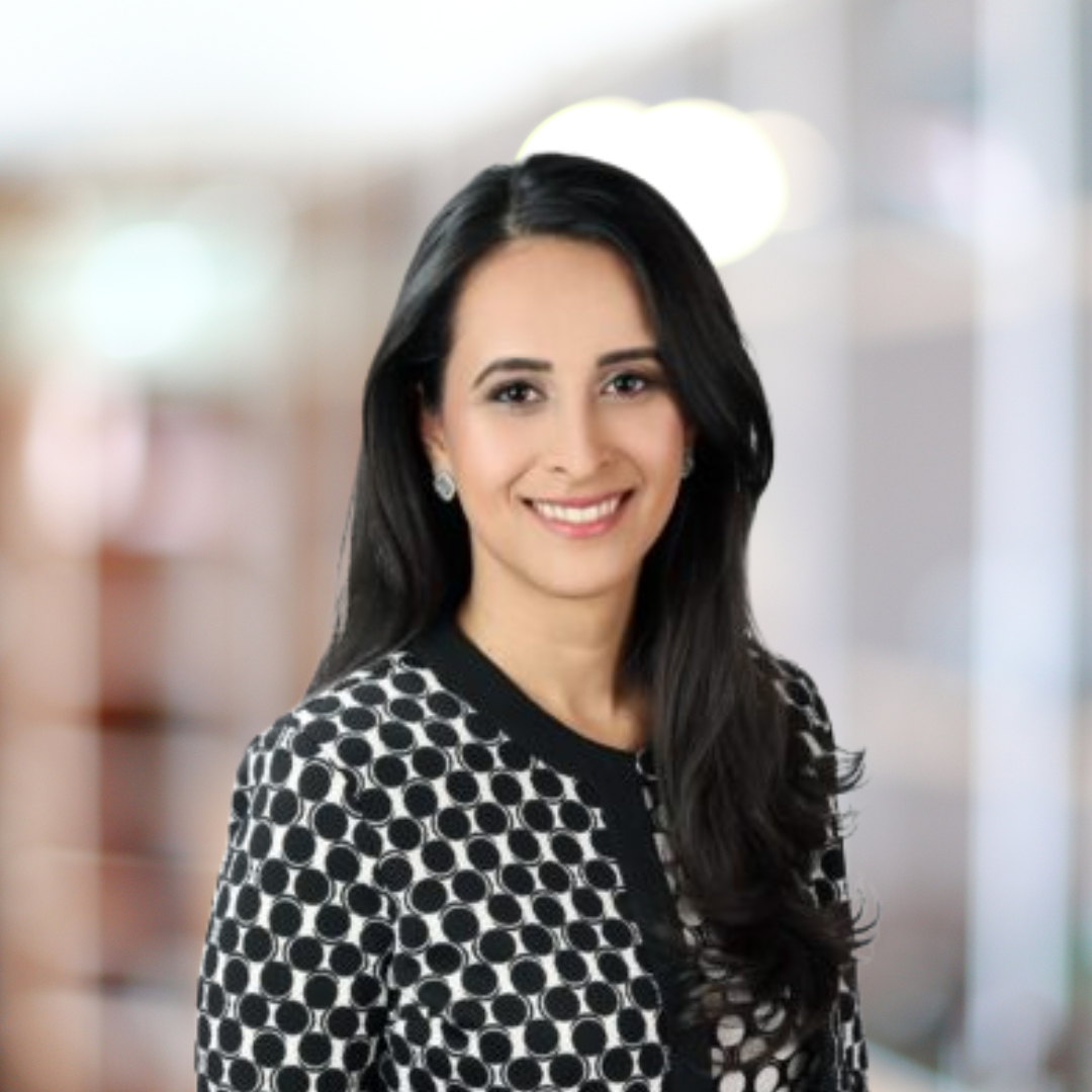 Headshot of Jenna Evans, a smiling woman with long, dark hair wears a polka dot jacket.