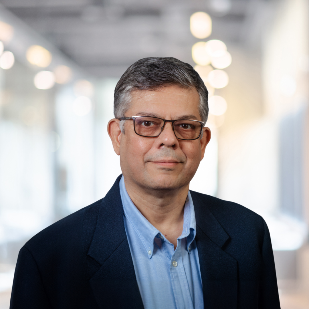 Headshot of Manish Kacker, a smiling man with short, graying hair, glasses, in a navy blazer.