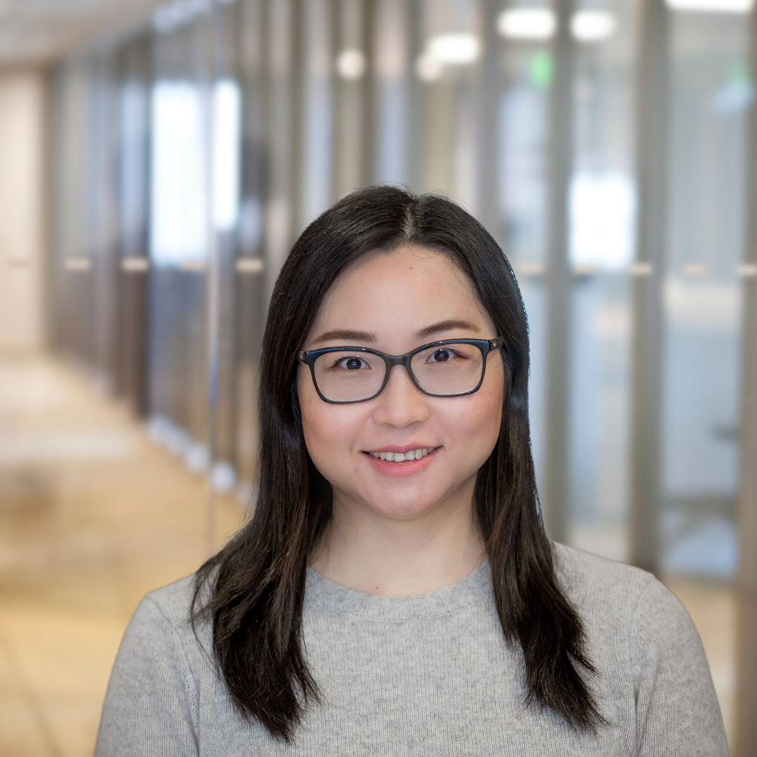Headshot of Yan Wang, a smiling woman with long, dark hair, glasses, wearing a light gray top.