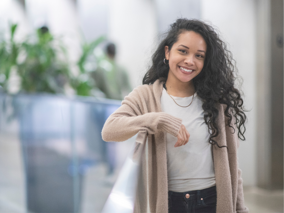 PhD student at the DeGroote School of Business, woman with curly hair in hallways leaning on a railing.